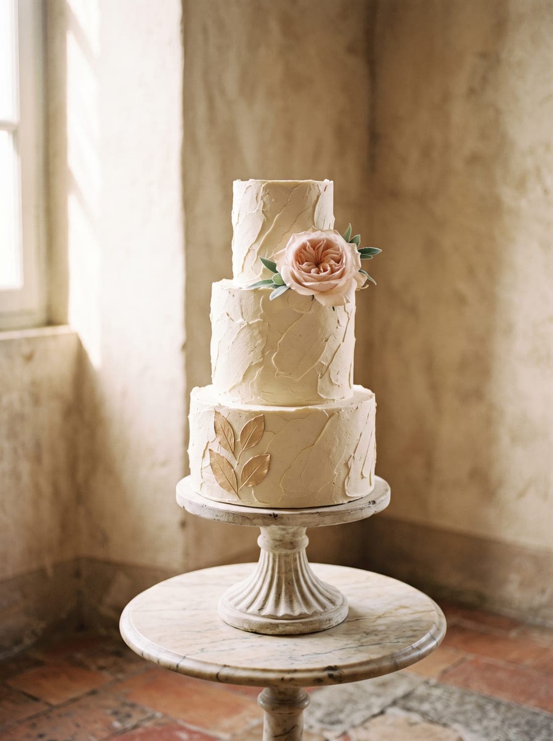 Eine dreistöckige Buttercreme-Hochzeitstorte mit einer einzelnen zartrosa Rose